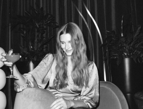 Black and white photo of a woman raising her cocktail glass