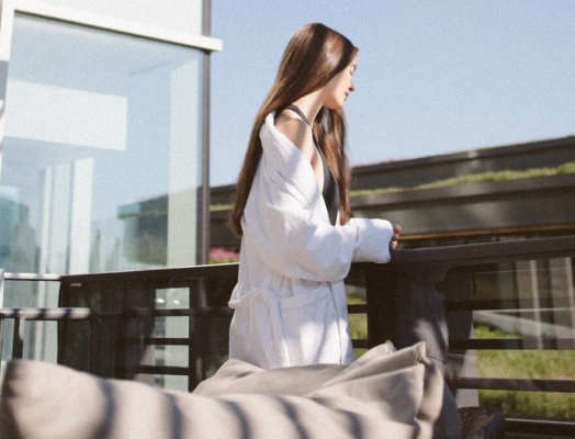Woman in white robe on hotel rooftop.