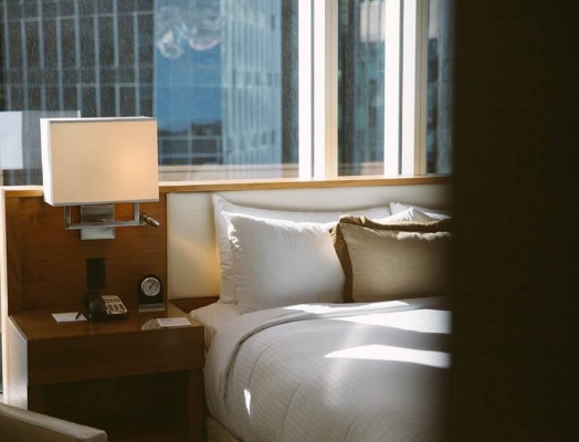 Hotel bed with sun shining in the window