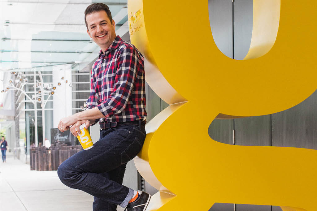 Todd Talbot leaning against a large "g" sculpture