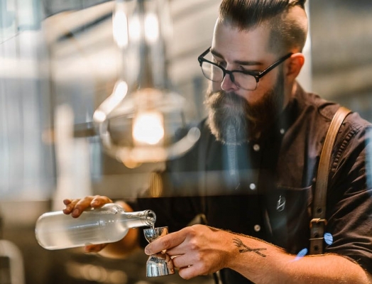 A man measuring a spirit in a jigger.