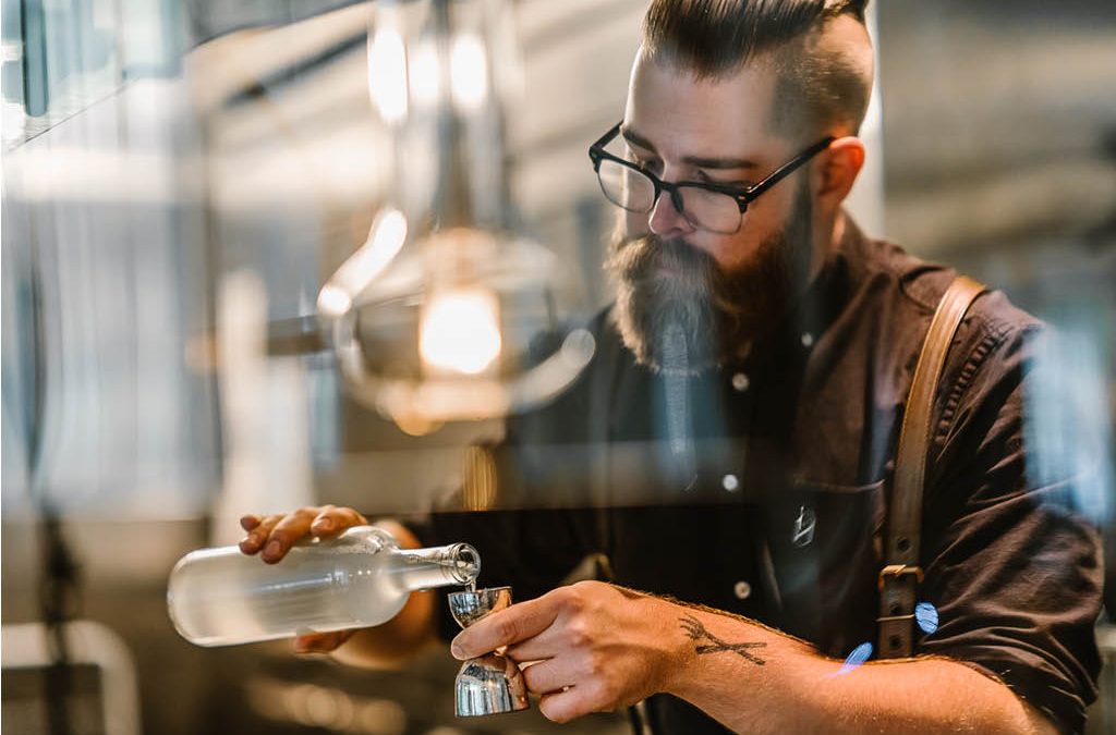 A man measuring a spirit in a jigger.