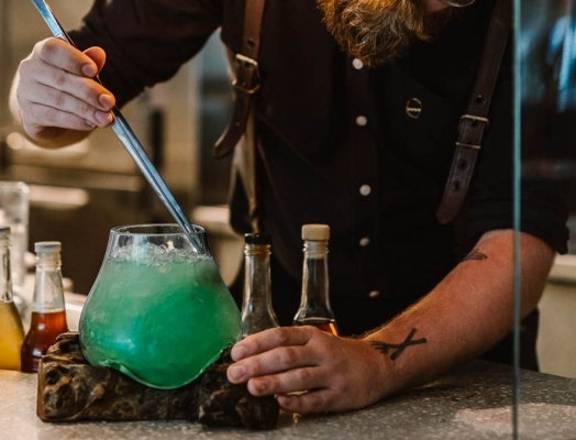 A bartender creating a green cocktail