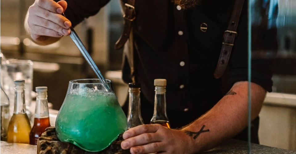 A bartender creating a green cocktail