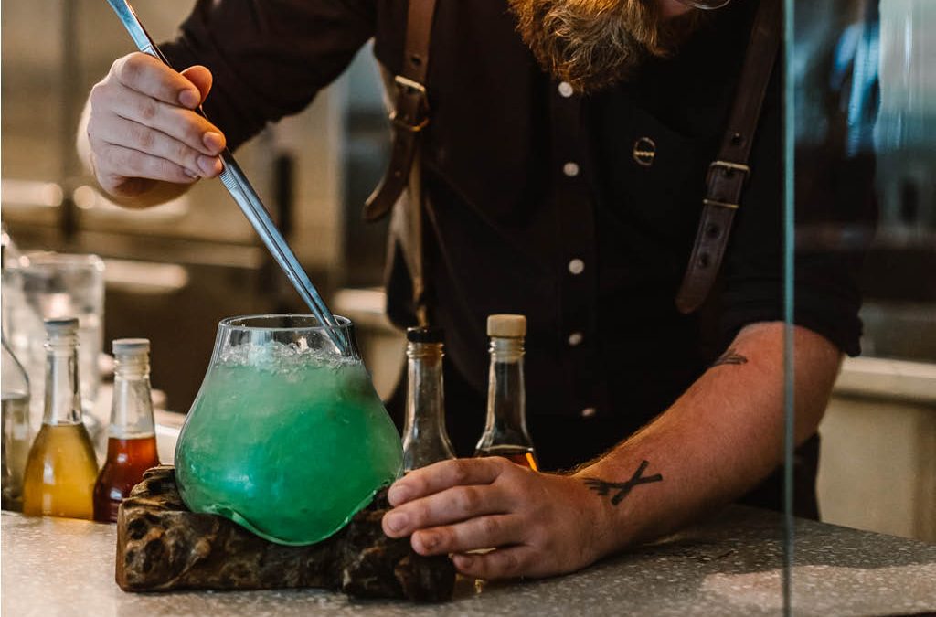 A bartender creating a green cocktail