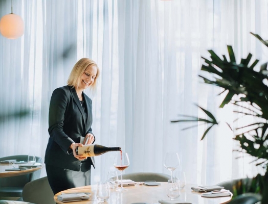 Mya Brown pouring a glass of wine at a set table