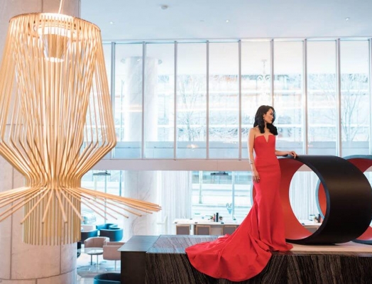 A woman in a red dress standing on a stage next to a sculpture.