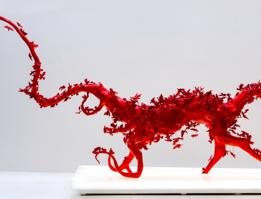 A red sculpture made of flowers on a white platform.