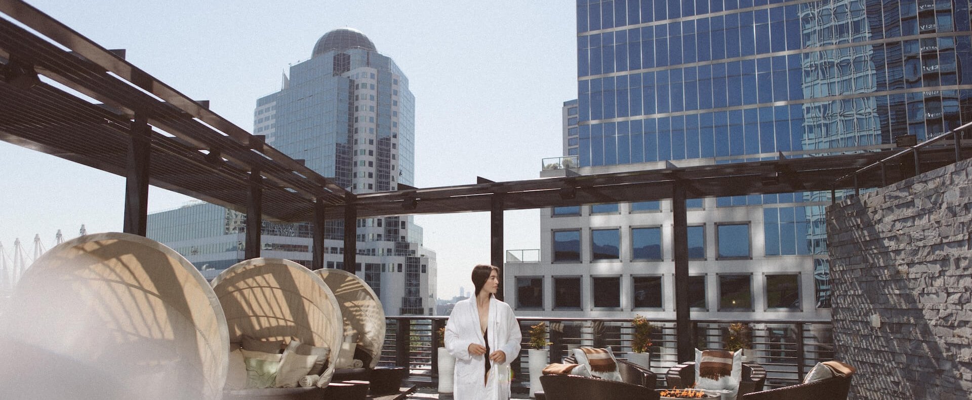 Woman walking through rooftop lounge area at a Fairmont Vancouver Spa