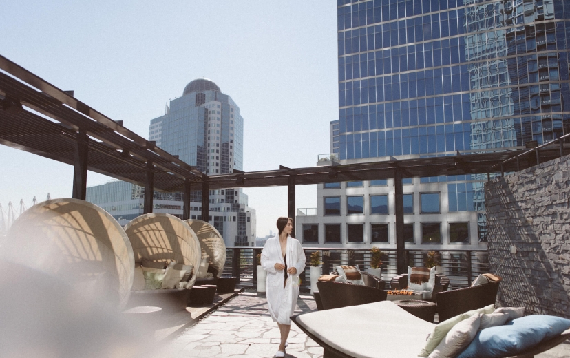 Woman walking through rooftop lounge area at a Fairmont Vancouver Spa