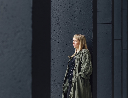 A blonde woman in a trench coat standing outside a building