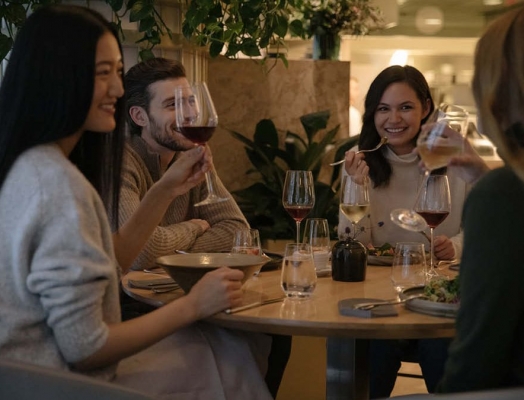 A group of friends drinking red wine around a table