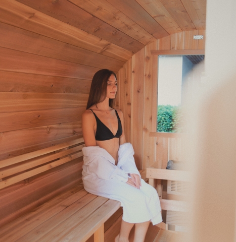 Woman sitting in cedar wood sauna in a robe