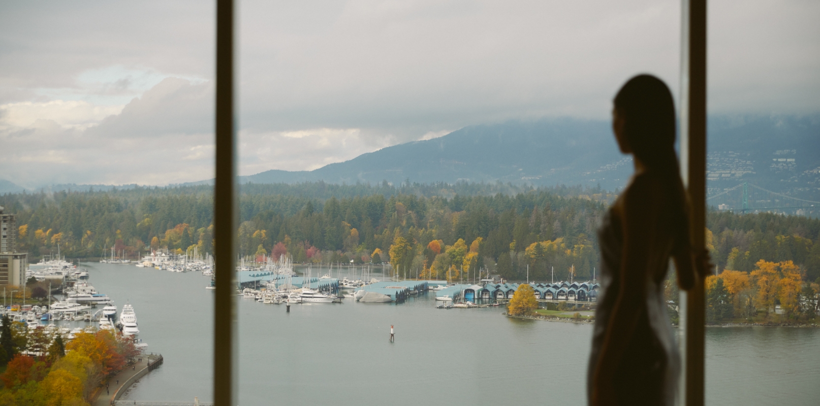 Woman looking out of window onto views of Vancouver and the North Shore mountains