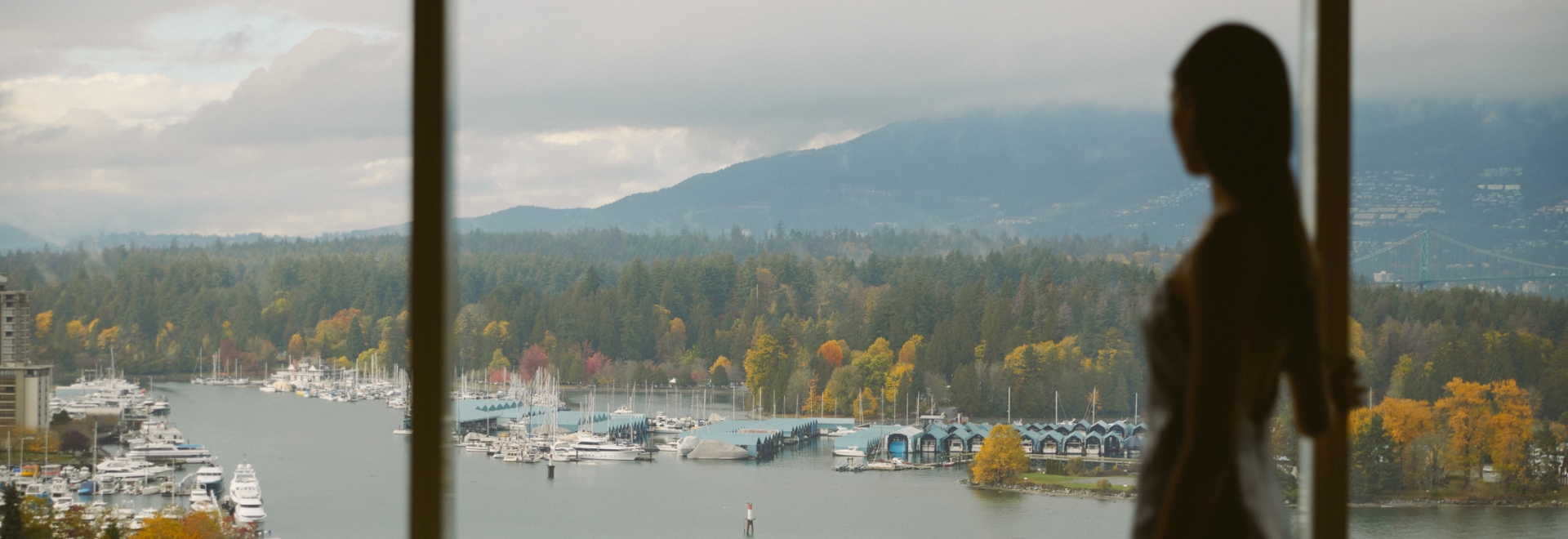Woman looking out of window onto views of Vancouver and the North Shore mountains