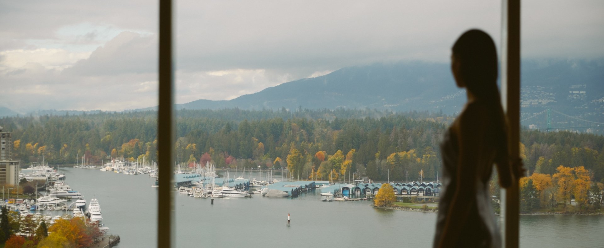 Woman looking out of window onto views of Vancouver and the North Shore mountains
