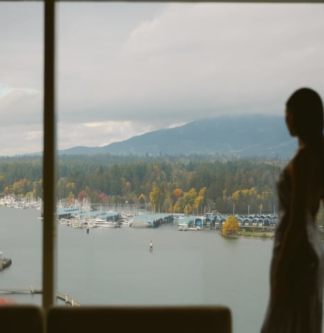 Woman looking out of window onto views of Vancouver and the North Shore mountains