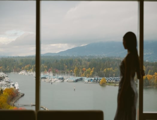 Woman looking out of window onto views of Vancouver and the North Shore mountains