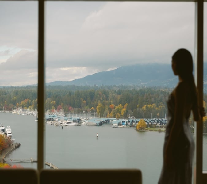 Woman looking out of window onto views of Vancouver and the North Shore mountains