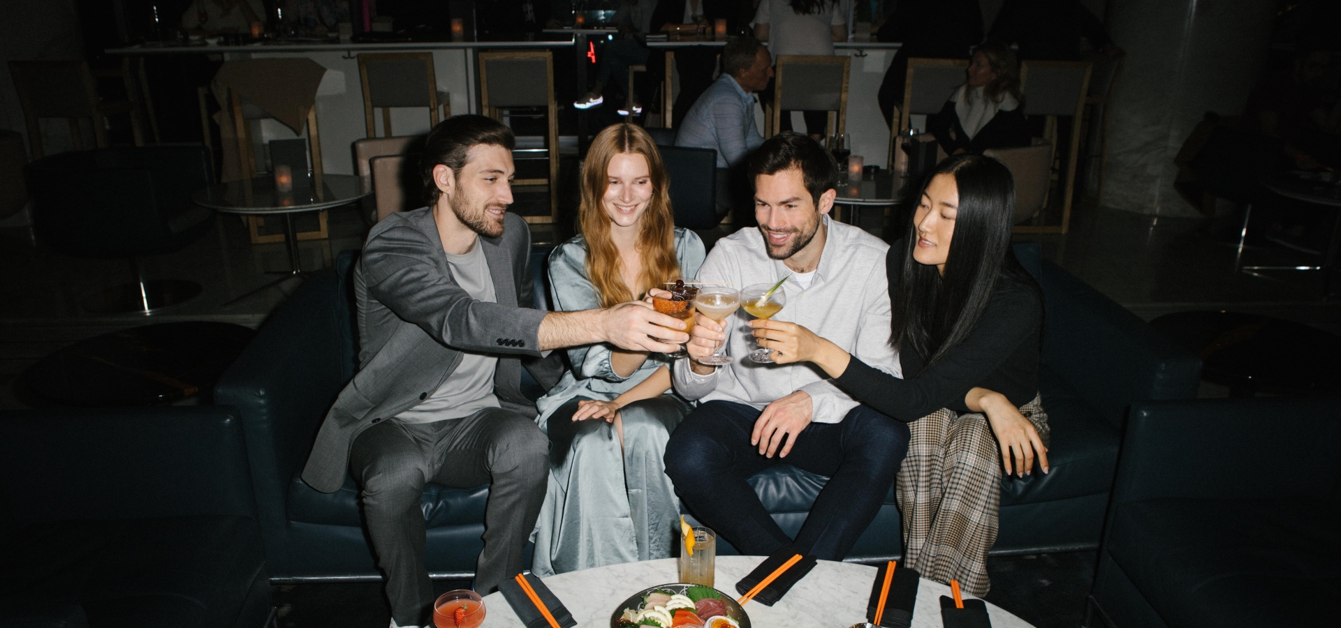 Group of four people cheersing cocktails in a lounge