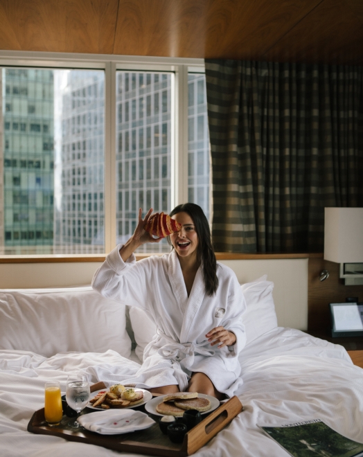 Woman inside downtown Vancouver luxury hotel enjoying in room dining food
