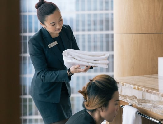 two housekeeping staff cleaning a luxury hotel bathroom