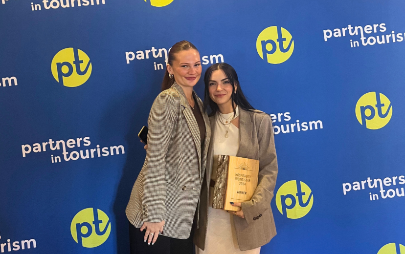 Two girls posing in front of sign with award